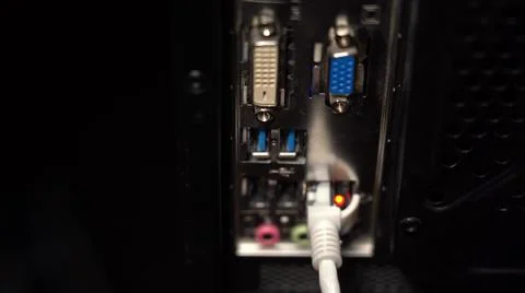 Hand inserts a lan wire into the computer. Stock Photos