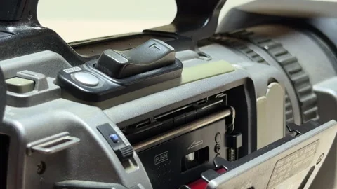 Hand Inserts MiniDV Cassette Into Camcorder Tape Deck During Indoor Session Stock Footage 331058274