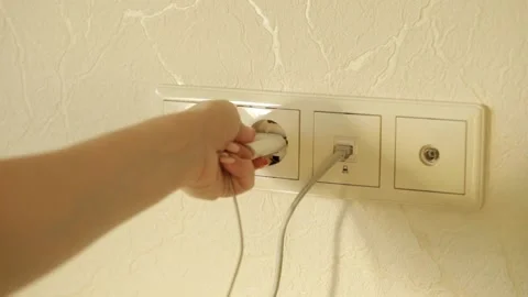Hand inserts the plug with the charging wire into the socket Stock Footage 144489808