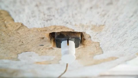The hand inserts the plug into the socket. An old building with a peeling clay Stock Footage 201256037