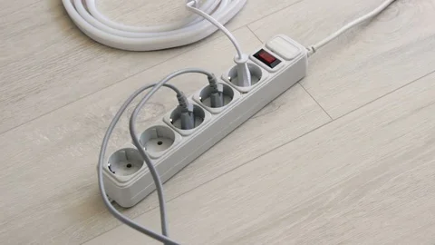 Hand inserts the plugs into the extension cord Surge Protector Stock Footage 128228975