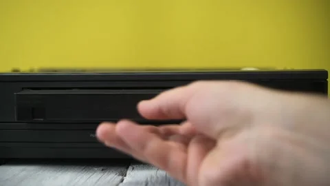 A hand inserts a video cassette into an old VCR. Stock Footage 183268038