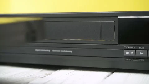 A hand inserts a video cassette into an old VCR. Video stock 183269994