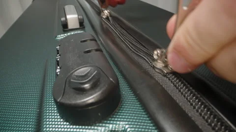 A Hand inserts the zipper pulls into the combination lock and adjusts the code, Stock Footage 282296207
