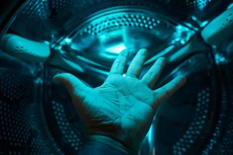A Hand inside washer in a blue light, concept Foto stock