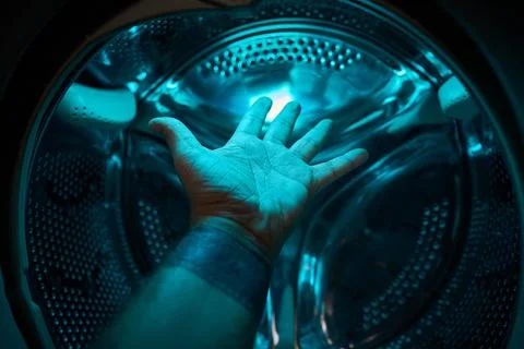 A Hand inside washer in a blue light, concept Stock Photos