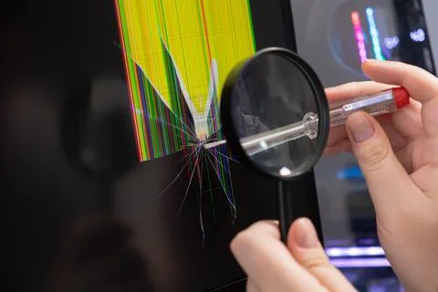 Hand inspecting a severely cracked computer screen with a magnifying glass,.. Foto stock