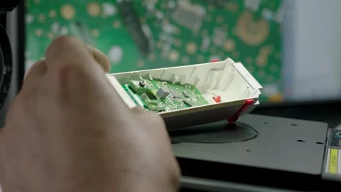 Hand Inspects Electronic Circuit Board in Plastic Case on Workbench Closeup Stock Footage 334053675