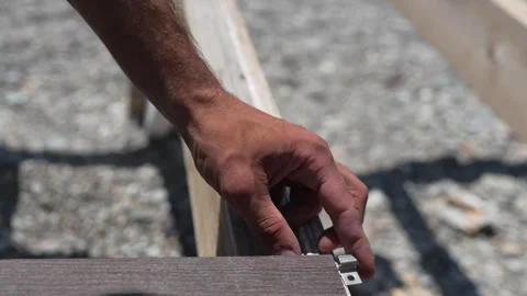 Hand Installing Bracket closeup on wood board outdoor during construction Stock Footage 315681603