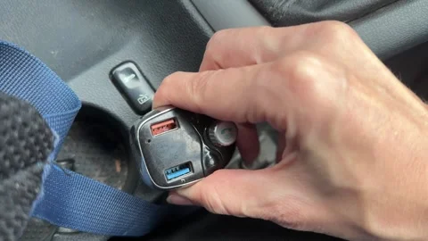 Hand installing car FM transmitter into vehicle console socket, connecting audio Stock Footage 337121842