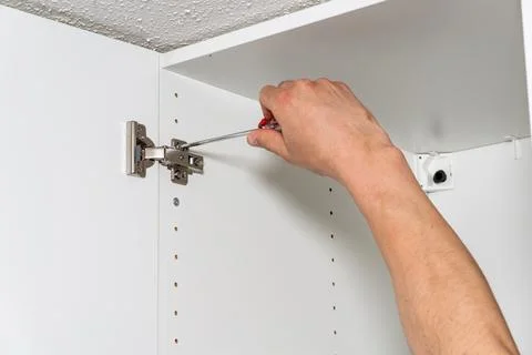 Hand installing hinge inside cabinet Fotos Stock