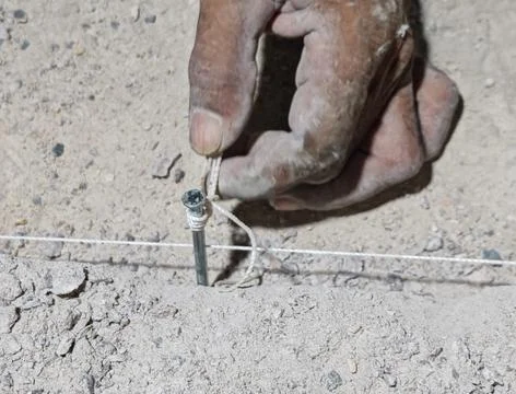 Hand installing metal nail with string line on concrete surface copy Фото