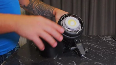 Hand installing protective cap on studio light close-up, securing lighting Stock Footage 333649541