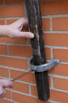 Hand installing timber post on brick wall Fotos de archivo