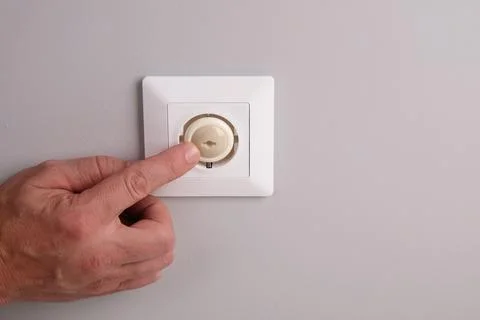 A hand installs a protective plug into an electrical outlet to protect childr Фото