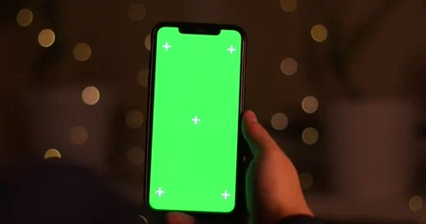Hand interacting with a green screen smartphone in a bokeh background Stock Footage 339071734