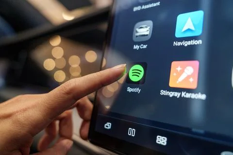 Hand interacting with the Spotify application in a BYD EV car Stock Photos