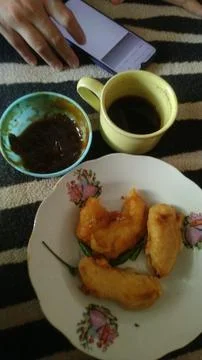 A hand interacts with a smartphone beside crispy fried snacks and hot coffee Fotos Stock