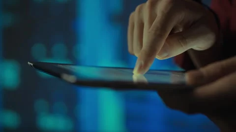 A hand interacts with a tablet in front of a blue background Stock Footage 288627184