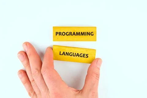 A hand interacts with yellow blocks displaying the words programming and lang Stockfoto's