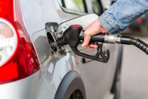 Hand in jeans jacket refueling gray metallic car on gas station - closeup wit Фото
