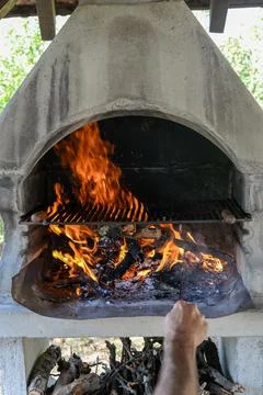 Hand keeps fire going in a grill with fiery flames - an empty fire grate Stock Photos