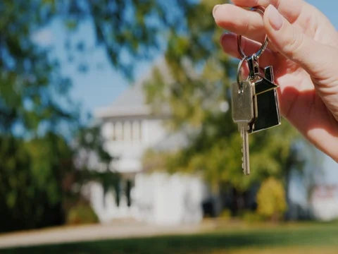 A hand with a keychain in the shape of a small house and keys. Against the Stock Footage 82056854
