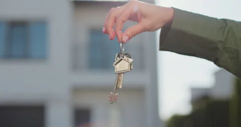 A hand with a keychain in the shape of a small house and keys against the Stock Footage 309089503