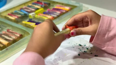 Hand of kid sharpening crayon close up, colorful art supplies nearby, Stock Footage 342748399
