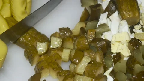 A hand with a knife cuts a pickled cucumber, close-up, on a cutting board 動画素材 229593704