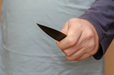 Hand with a knife. Middle section of a man holding a sharp knife. Selective f Stock Photos