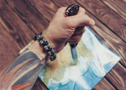 Hand with knife pointing to map. Stock Photos