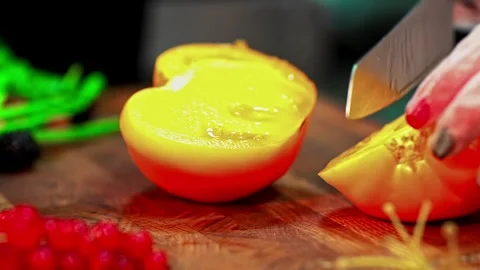 Hand with knife slices soft ripe tomato on board with seeds and pulp visible Vidéo 332759452