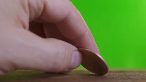 Hand knocks vintage wooden table with a vintage Victorian coin on green screen Stock Footage