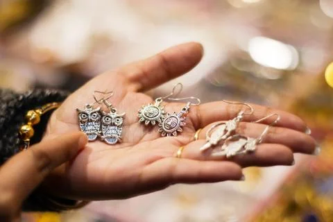 Hand of a lady selecting ear rings metal junk jewellery at a shop. Foto stock
