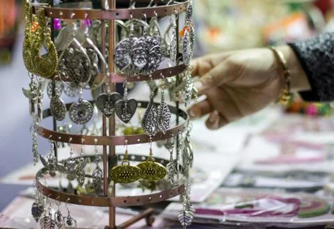 Hand of a lady selecting ear rings metal junk jewellery at a shop. Foto stock