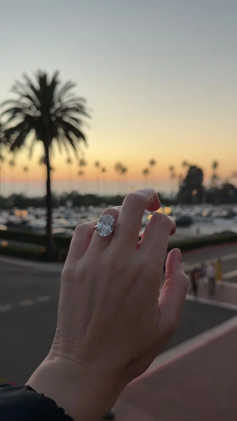 Hand with large oval diamond solitaire engagement ring at sunset Newport Beach 스톡 동영상 325876388
