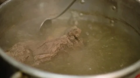 A hand with a large spoon stirring Meat stew Stock Footage 87868396