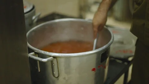 A hand with a large spoon stirring red soup Stock Footage 87869530
