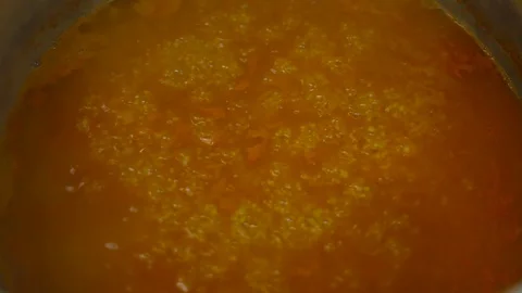 A hand with a large spoon stirring red soup Stock Footage 87869557