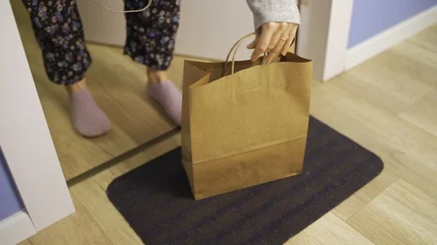 Hand with latex glove drops off package or food takeout bag - woman picks it up Stock Footage 128780366