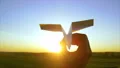 The hand launches paper plane to the sky on the bright sunrise background 4k or 4k+ Resolution