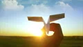 The hand launches the paper plane to the sky on the sunrise background 4k or 4k+ Resolution