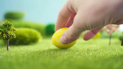 Hand laying easter egg on grass in fairytale fictional macrocosm Stock Footage 150303631