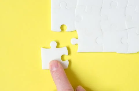 Hand lays down the missing piece of the puzzle. Last piece of jigsaw puzzle Stock Photos