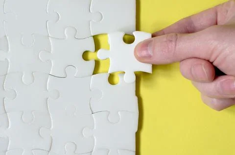 The hand lays down the missing piece of the puzzle. Last piece of jigsaw puzz Stock Photos