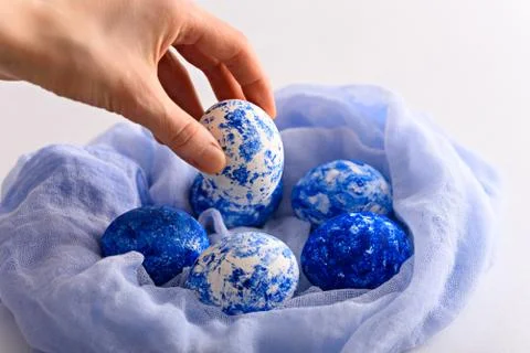 Hand lays Easter egg in the color of the year classic blue with gradient effe Stock Photos