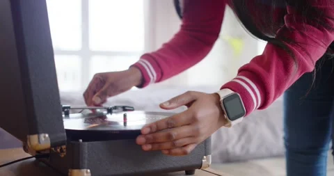 Hand is leaning from right and placing vinyl record on portable turntable beside Stock Footage 342953562