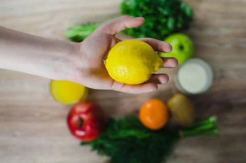 In the hand of the lemon on a background of vegetables Stock Photos
