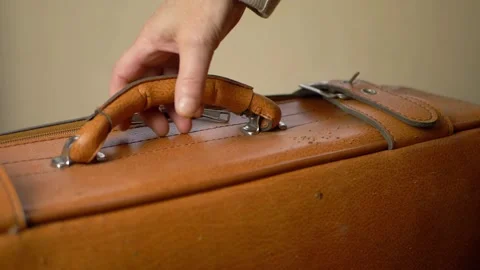 Hand lifting brown suitcase by handle close up shot Vidéo 137977520